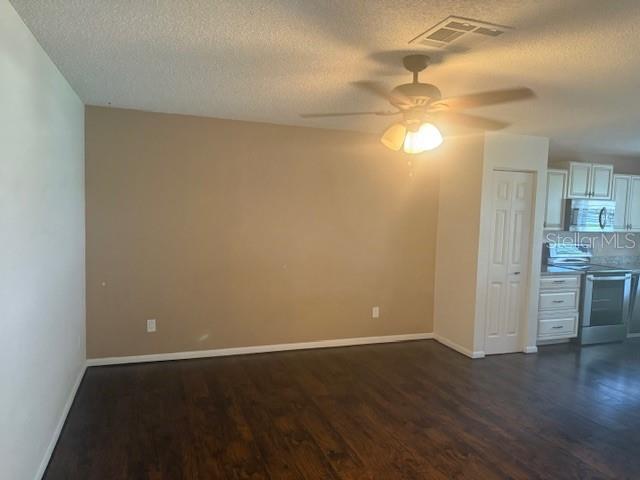 9722 SW 95th Ct Unit C, Ocala, FL 34481 - unfurnished living room featuring a textured ceiling, dark wood-type flooring, and ceiling fan