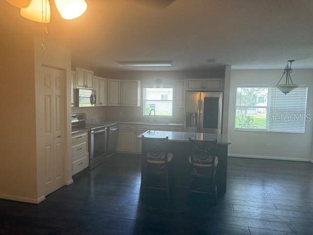 9722 SW 95th Ct Unit C, Ocala, FL 34481 - kitchen with appliances with stainless steel finishes, dark wood finished floors, white cabinetry, a center island, and hanging light fixtures