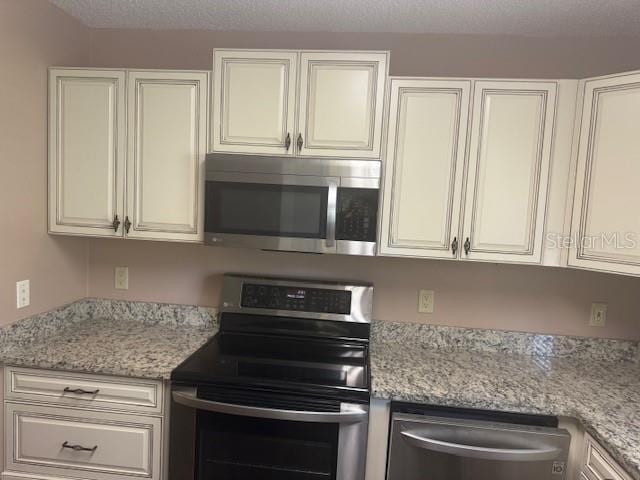 9722 SW 95th Ct Unit C, Ocala, FL 34481 - kitchen with appliances with stainless steel finishes, white cabinets, and light stone countertops
