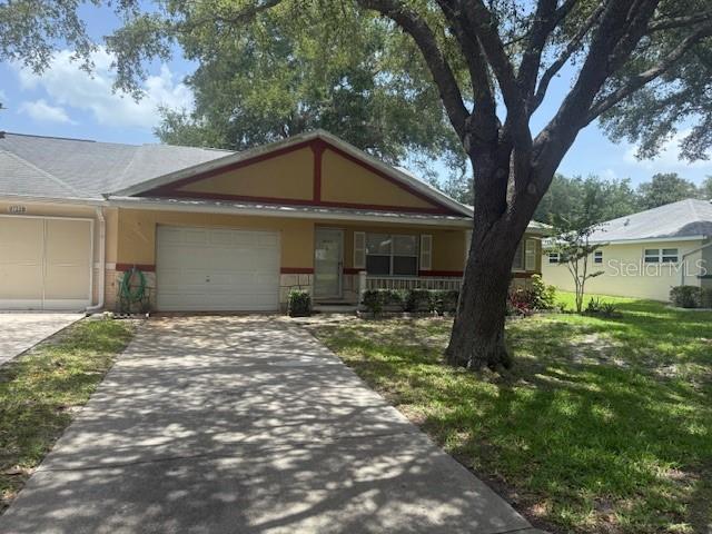 9722 SW 95th Ct Unit C, Ocala, FL 34481 - view of front facade with an attached garage, driveway, a porch, brick siding, and a front lawn