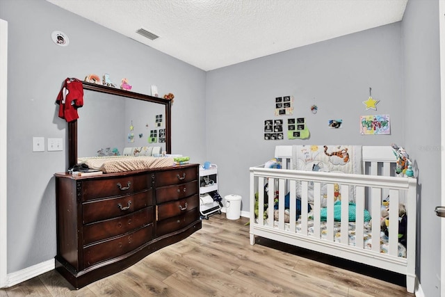 6816 Thomas Cir, Tampa, FL 33619 - bedroom featuring wood finished floors, a nursery area, and a textured ceiling