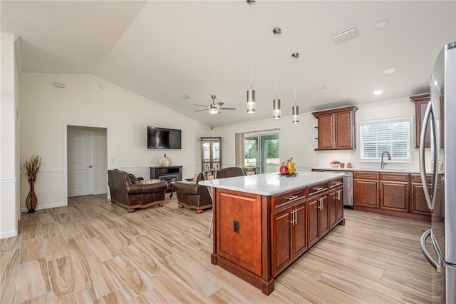 5331 SW 121st Ter, Ocala, FL 34481 - kitchen with stainless steel appliances, ornamental molding, a glass covered fireplace, open floor plan, and light countertops