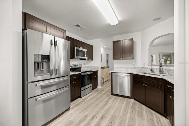 9735 SW 96th St, Ocala, FL 34481 - kitchen featuring stainless steel appliances, arched walkways, dark brown cabinets, light wood-style floors, and a textured ceiling