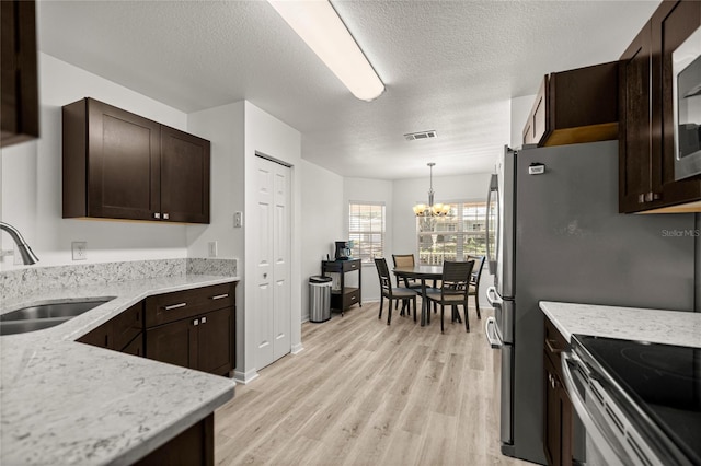 9735 SW 96th St, Ocala, FL 34481 - kitchen with a chandelier, light wood-style floors, dark brown cabinets, light stone countertops, and a textured ceiling