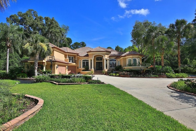 695 SE 47th Loop, Ocala, FL 34480 - mediterranean / spanish home with curved driveway, stucco siding, a front yard, and a garage