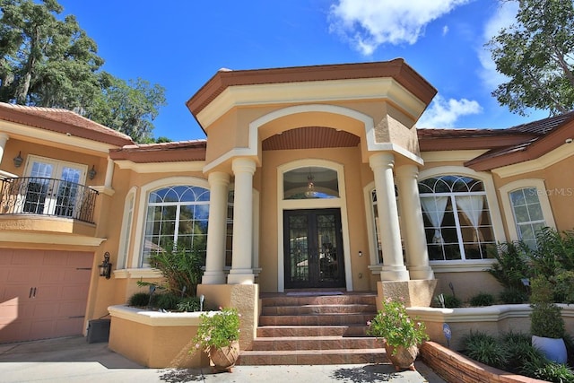 695 SE 47th Loop, Ocala, FL 34480 - entrance to property with french doors, stucco siding, an attached garage, a tiled roof, and a balcony