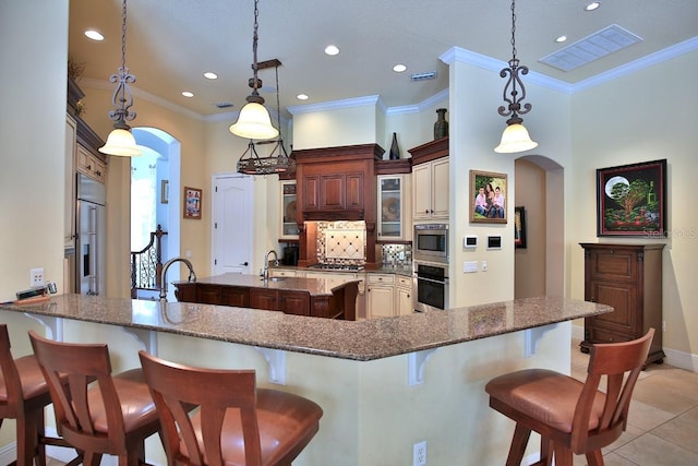 695 SE 47th Loop, Ocala, FL 34480 - kitchen featuring stainless steel appliances, arched walkways, a breakfast bar area, a peninsula, and glass insert cabinets