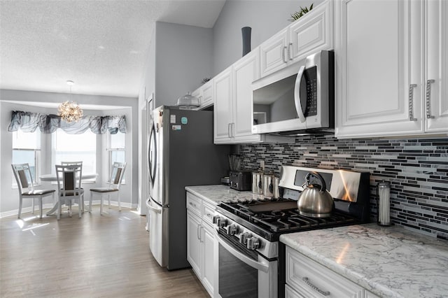 1584 Silhouette Dr, Clermont, FL 34711 - kitchen featuring appliances with stainless steel finishes, a chandelier, decorative backsplash, white cabinets, and wood finished floors