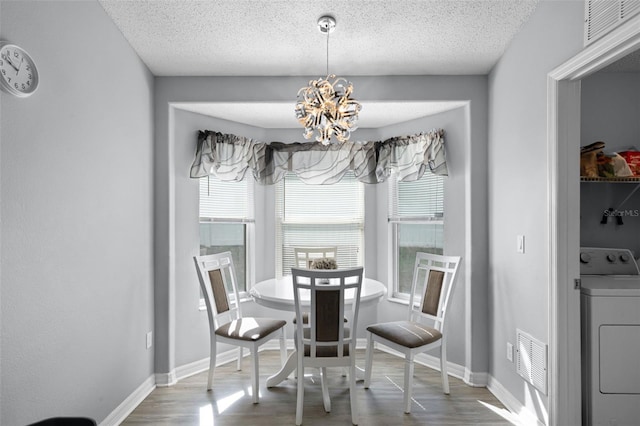 1584 Silhouette Dr, Clermont, FL 34711 - dining space with washer / dryer, wood finished floors, a chandelier, healthy amount of natural light, and a textured ceiling