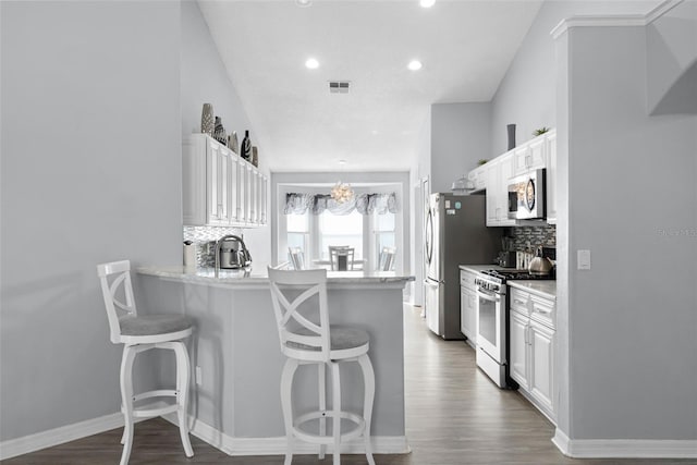 1584 Silhouette Dr, Clermont, FL 34711 - kitchen featuring appliances with stainless steel finishes, a kitchen bar, white cabinetry, and recessed lighting