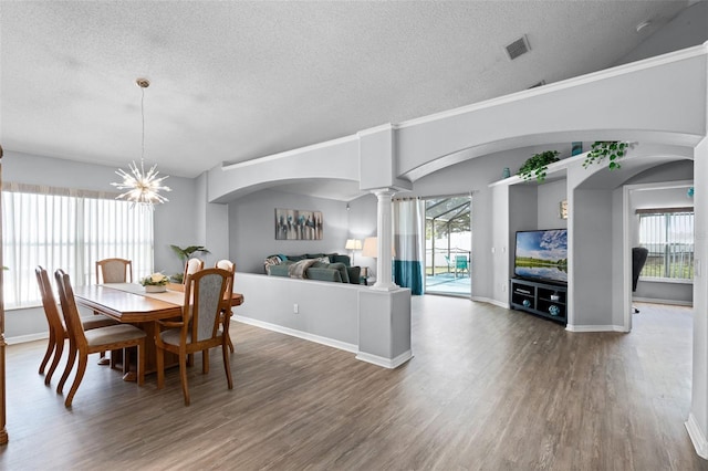 1584 Silhouette Dr, Clermont, FL 34711 - dining space with a textured ceiling, wood finished floors, decorative columns, and a chandelier