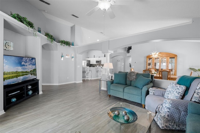 1584 Silhouette Dr, Clermont, FL 34711 - living area with arched walkways, a ceiling fan, ornate columns, wood finished floors, and high vaulted ceiling