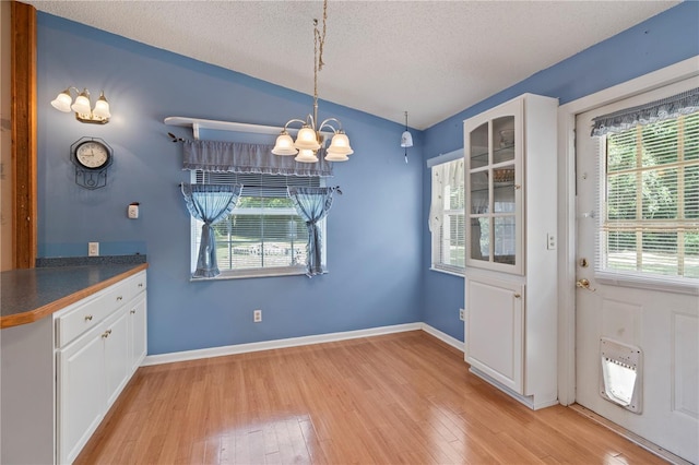 206 N Dundee Way, Inverness, FL 34450 - unfurnished dining area with a chandelier, light wood-style floors, a textured ceiling, heating unit, and lofted ceiling