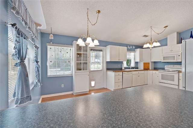 206 N Dundee Way, Inverness, FL 34450 - kitchen featuring white appliances, a chandelier, a textured ceiling, white cabinets, and dark countertops