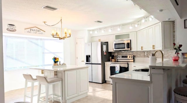 2550 SW Ivy Pl, Dunnellon, FL 34431 - kitchen featuring stainless steel appliances, a breakfast bar area, decorative backsplash, a chandelier, and glass insert cabinets