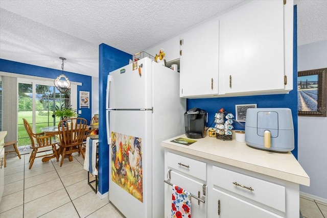7961 Midway Drive Ter Unit J102, Ocala, FL 34472 - kitchen with freestanding refrigerator, a textured ceiling, white cabinets, light countertops, and light tile patterned flooring