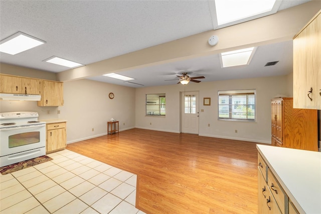 8704 SW 94th Ln Unit G, Ocala, FL 34481 - kitchen with white range with electric cooktop, under cabinet range hood, light brown cabinets, light countertops, and light wood-style floors