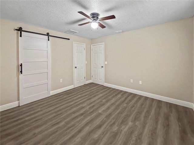 5 Bahia Circle Pl, Ocala, FL 34472 - unfurnished bedroom with a barn door, a textured ceiling, dark wood-type flooring, and a ceiling fan