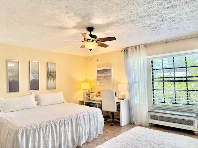 502 SE Guava Ter, Port St Lucie, FL 34983 - bedroom with a textured ceiling, a desk, a ceiling fan, and tile patterned flooring