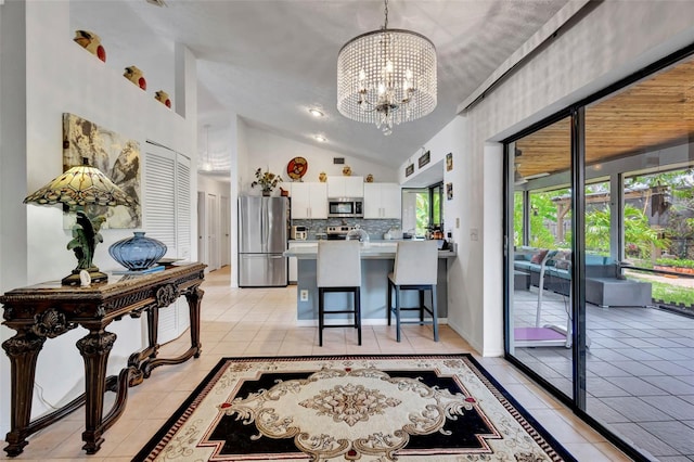 502 SE Guava Ter, Port St Lucie, FL 34983 - kitchen featuring stainless steel appliances, light tile patterned floors, a chandelier, white cabinetry, and high vaulted ceiling