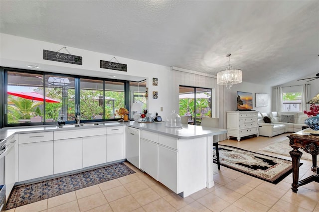 502 SE Guava Ter, Port St Lucie, FL 34983 - kitchen featuring a peninsula, dishwasher, open floor plan, a chandelier, and white cabinetry