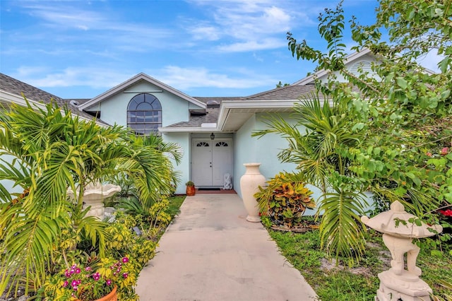 502 SE Guava Ter, Port St Lucie, FL 34983 - view of exterior entry featuring stucco siding and roof with shingles