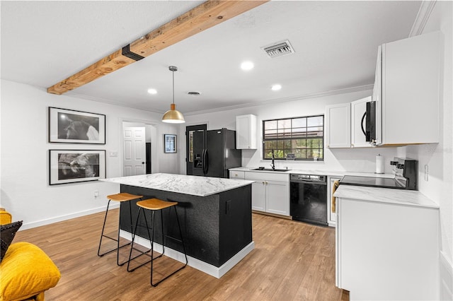 802 NE 39th Ct, Ocala, FL 34470 - kitchen featuring black appliances, white cabinetry, beam ceiling, a center island, and a breakfast bar area