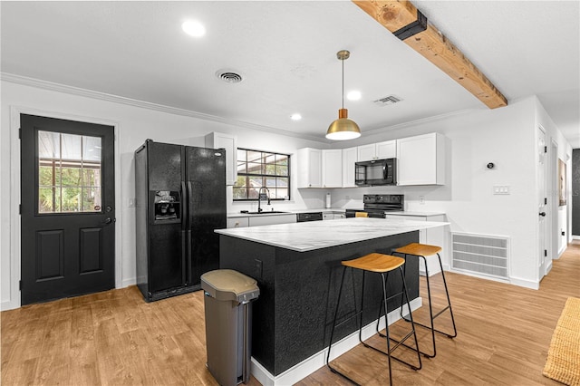 802 NE 39th Ct, Ocala, FL 34470 - kitchen featuring black appliances, white cabinetry, a kitchen island, light wood-style flooring, and light countertops