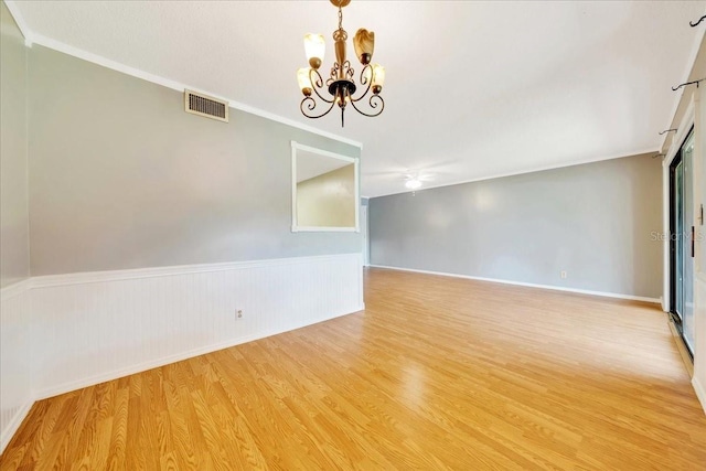 683 Midway Dr Unit B, Ocala, FL 34472 - spare room featuring a chandelier, light wood finished floors, a wainscoted wall, and crown molding