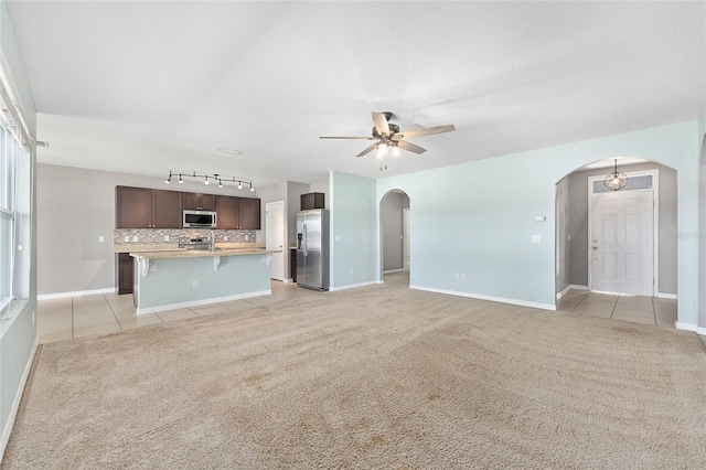 7054 SW 64th Ter, Ocala, FL 34476 - unfurnished living room featuring arched walkways, light colored carpet, ceiling fan, rail lighting, and light tile patterned floors