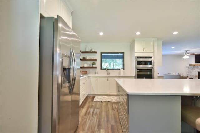 2855 SE 38th St, Ocala, FL 34480 - kitchen with appliances with stainless steel finishes, light countertops, wood finished floors, white cabinets, and ceiling fan