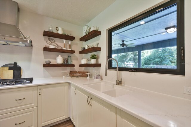 2855 SE 38th St, Ocala, FL 34480 - kitchen featuring wall chimney exhaust hood, stainless steel gas stovetop, light countertops, white cabinets, and a textured ceiling