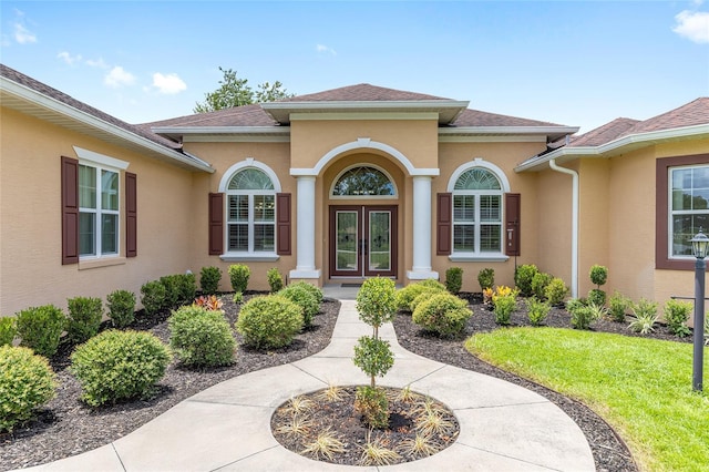 5024 SW 114th Street Rd, Ocala, FL 34476 - doorway to property featuring french doors, stucco siding, a shingled roof, and a lawn