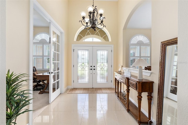 5024 SW 114th Street Rd, Ocala, FL 34476 - foyer entrance with french doors, a high ceiling, arched walkways, a chandelier, and light tile patterned floors
