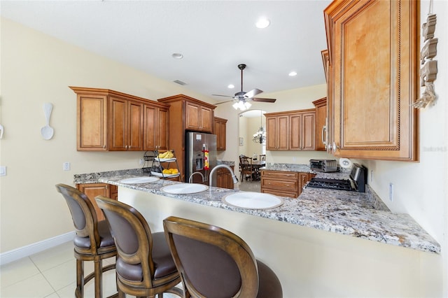 5024 SW 114th Street Rd, Ocala, FL 34476 - kitchen featuring appliances with stainless steel finishes, a ceiling fan, a peninsula, a breakfast bar area, and brown cabinets
