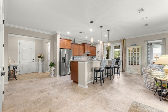 9925 SW 95th Loop, Ocala, FL 34481 - kitchen with high quality fridge, brown cabinetry, a breakfast bar area, a kitchen island with sink, and ornamental molding