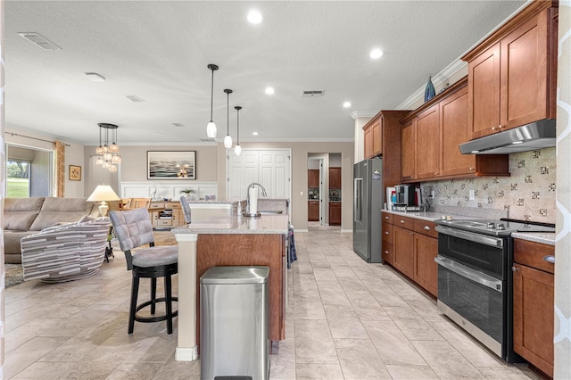 9925 SW 95th Loop, Ocala, FL 34481 - kitchen with stainless steel appliances, under cabinet range hood, ornamental molding, brown cabinets, and open floor plan