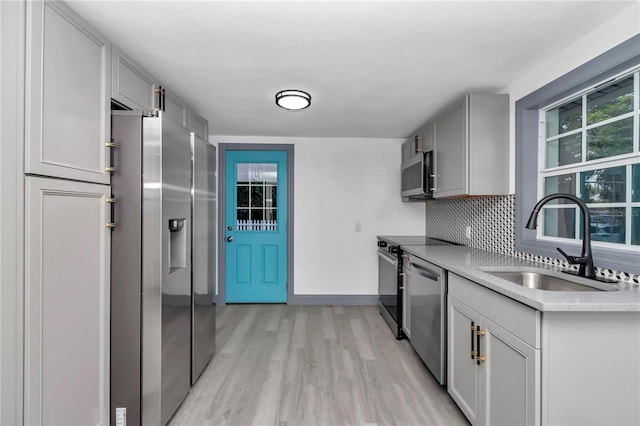 1636 SW 5th Pl, Ocala, FL 34471 - kitchen featuring appliances with stainless steel finishes, light wood-style flooring, decorative backsplash, light countertops, and gray cabinetry