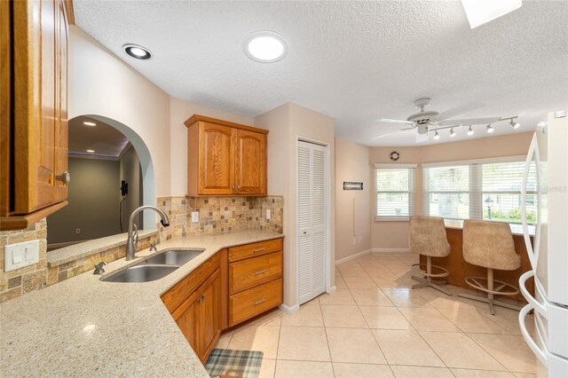9085 SW 96th Ln Unit B, Ocala, FL 34481 - kitchen featuring decorative backsplash, freestanding refrigerator, brown cabinets, a textured ceiling, and a ceiling fan