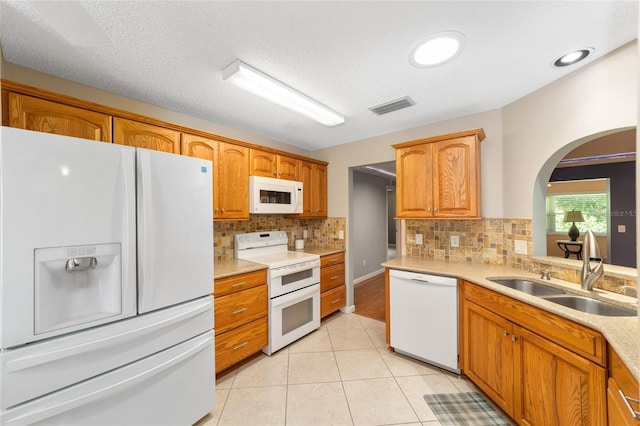 9085 SW 96th Ln Unit B, Ocala, FL 34481 - kitchen featuring white appliances, arched walkways, backsplash, light countertops, and light tile patterned floors