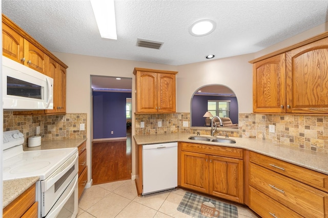 9085 SW 96th Ln Unit B, Ocala, FL 34481 - kitchen featuring white appliances, decorative backsplash, light tile patterned floors, brown cabinetry, and a textured ceiling