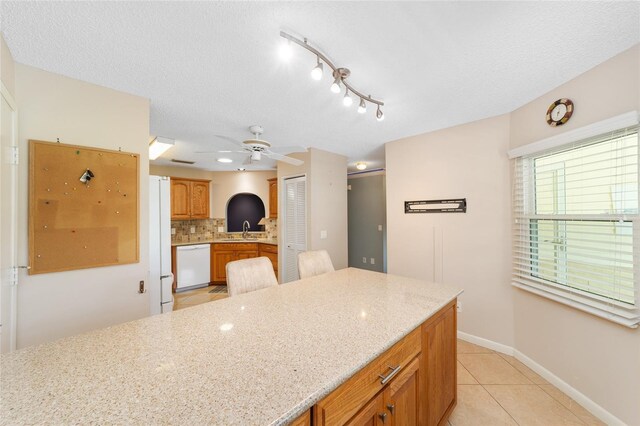 9085 SW 96th Ln Unit B, Ocala, FL 34481 - kitchen with white appliances, a ceiling fan, light tile patterned flooring, decorative backsplash, and light stone countertops