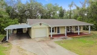 7808 E Savannah Dr, Floral City, FL 34436 - view of front facade featuring a carport, covered porch, driveway, and a front lawn