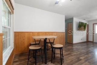 7808 E Savannah Dr, Floral City, FL 34436 - dining area with a wainscoted wall, wooden walls, dark wood-style flooring, and ceiling fan