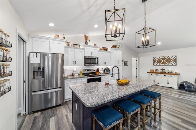 7435 N Nature Trl, Hernando, FL 34442 - kitchen featuring appliances with stainless steel finishes, vaulted ceiling, white cabinets, an island with sink, and dark wood-style flooring