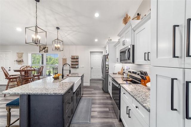 7435 N Nature Trl, Hernando, FL 34442 - kitchen with appliances with stainless steel finishes, a kitchen island with sink, a breakfast bar area, dark wood finished floors, and white cabinets