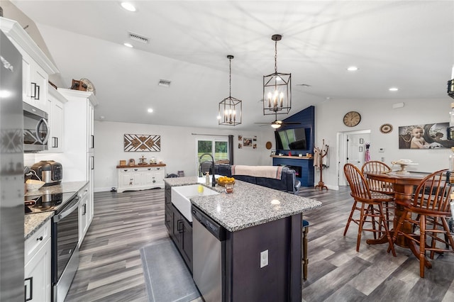 7435 N Nature Trl, Hernando, FL 34442 - kitchen with appliances with stainless steel finishes, vaulted ceiling, a chandelier, dark wood-style flooring, and white cabinets