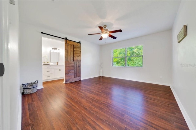 6142 SE 37th Ter, Ocala, FL 34480 - unfurnished bedroom featuring a barn door, dark wood finished floors, connected bathroom, and a ceiling fan