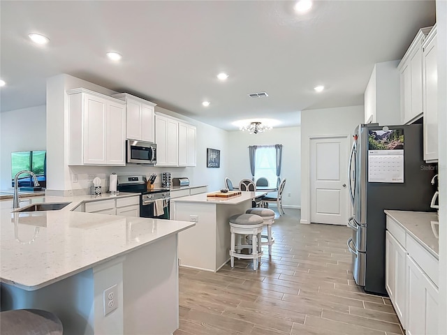 19424 SW 77th Loop, Dunnellon, FL 34432 - kitchen featuring appliances with stainless steel finishes, a kitchen bar, a peninsula, a kitchen island, and white cabinetry