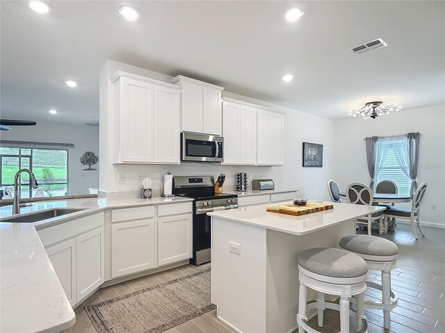 19424 SW 77th Loop, Dunnellon, FL 34432 - kitchen featuring appliances with stainless steel finishes, a breakfast bar, light wood finished floors, recessed lighting, and white cabinets